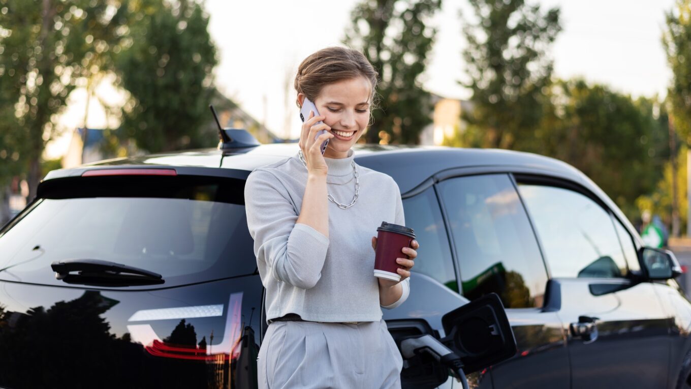 Young woman with an electric car at charging station in Chisinau, Moldova