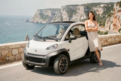 Mini Moke électrique garée sur une route côtière méditerranéenne avec une femme appuyée contre le capot