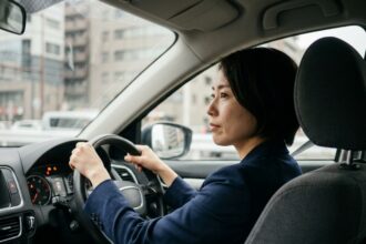 Femme concentrée au volant avec les deux mains sur le volant, adoptant une conduite sécurisée en ville